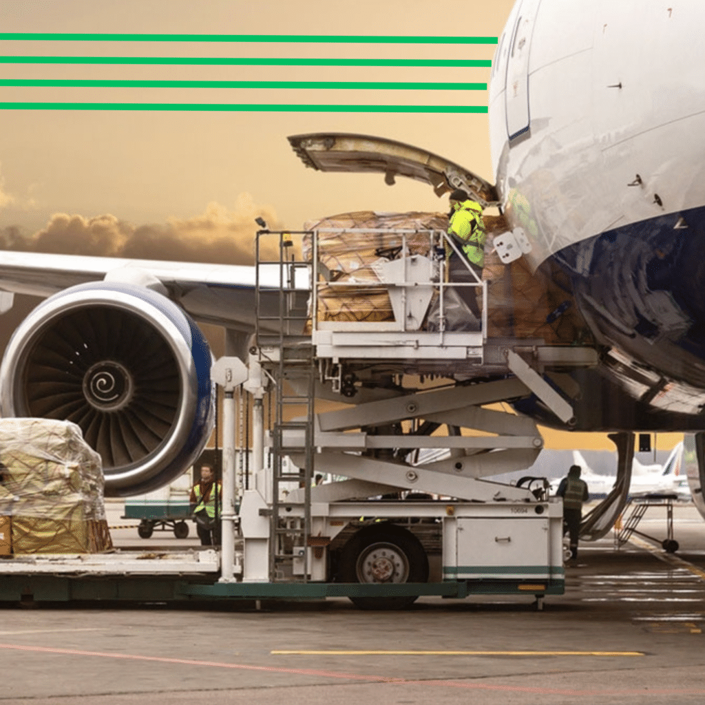 A high-loader vehicle lifting wrapped cargo pallets into the open belly compartment of a commercial freight airplane on an airport tarmac.