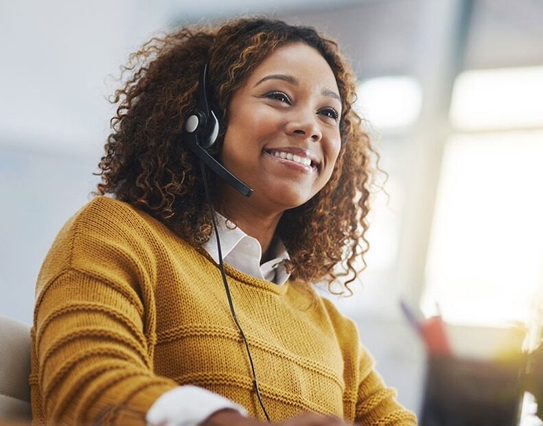 A smiling customer support representative wearing a headset, providing friendly and helpful assistance to a client over the phone.